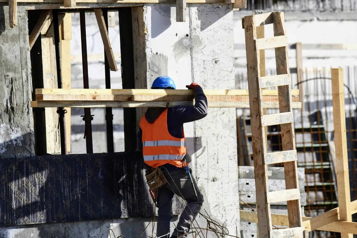 construction worker carrying 2x4s