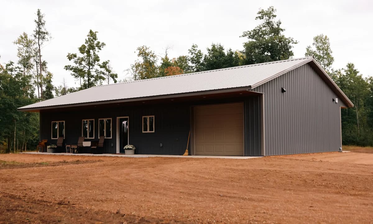 Dark gray Craftsman home with a metal roof, covered front porch, and attached garage