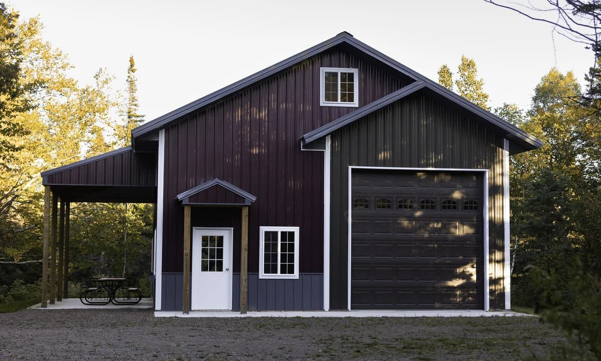 Tall dark man cave building with a large garage door and covered side patio