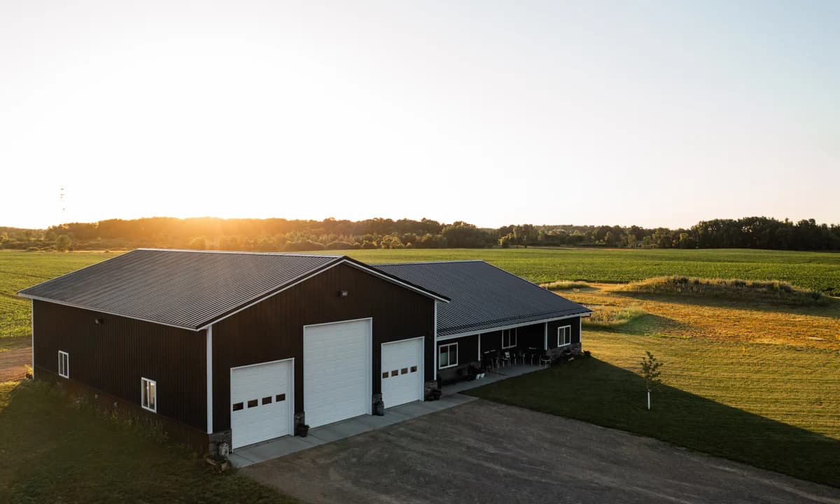 Barndominium at sunset with a residential wing and three white garage doors