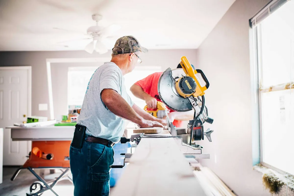 man measuring and sawing wood indoors
