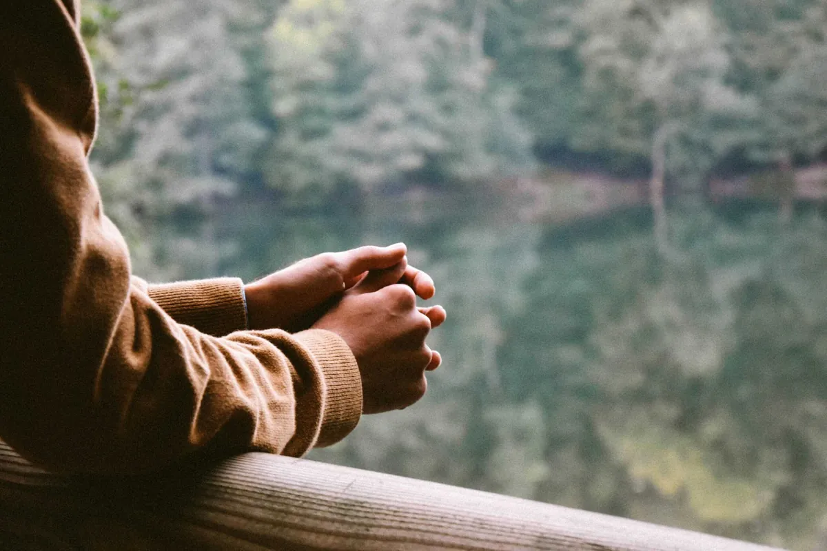 man's arms leaning on railing